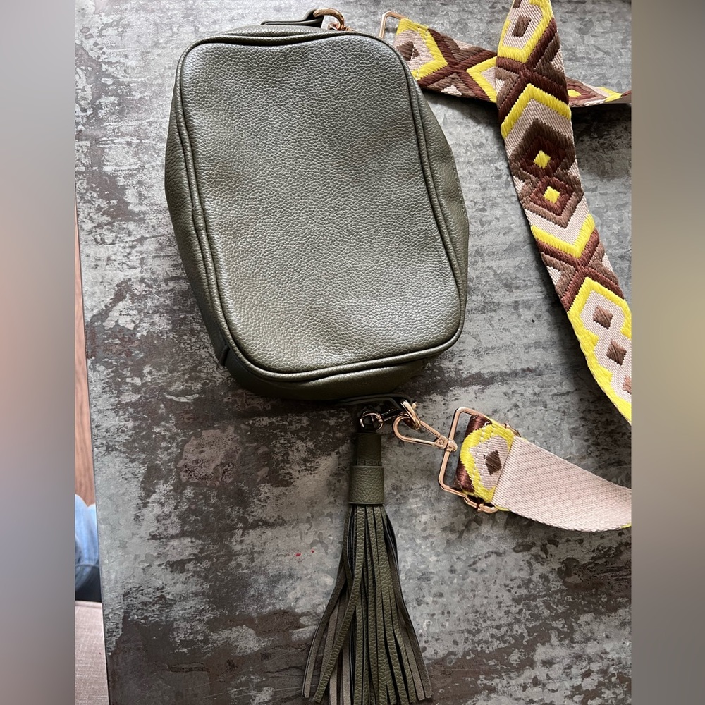 Green camera style cross body bag with tassel and wide strap